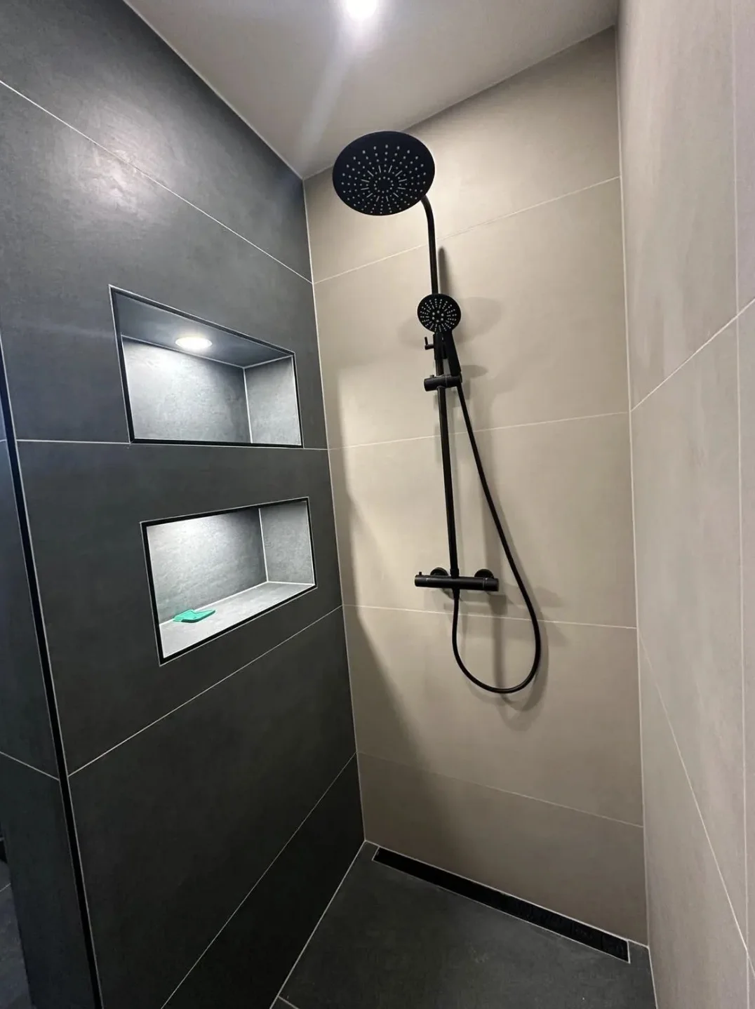 Douche met donkere accentwand, zwarte kranen en ingebouwde nissen