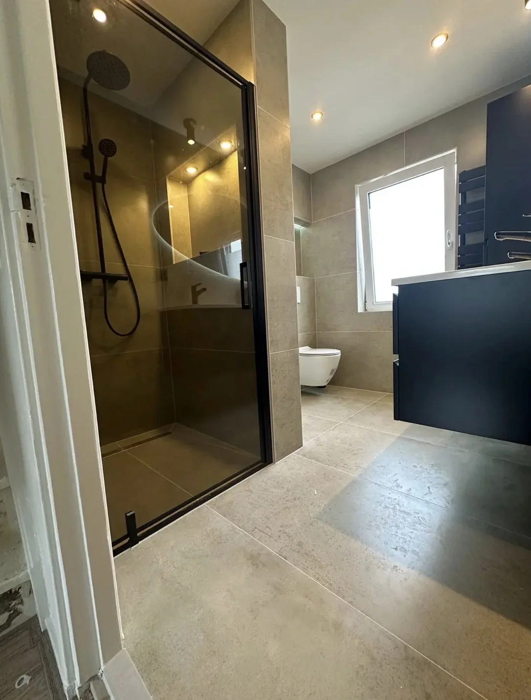 Badkamer met glazen douchewand en donker wastafelmeubel